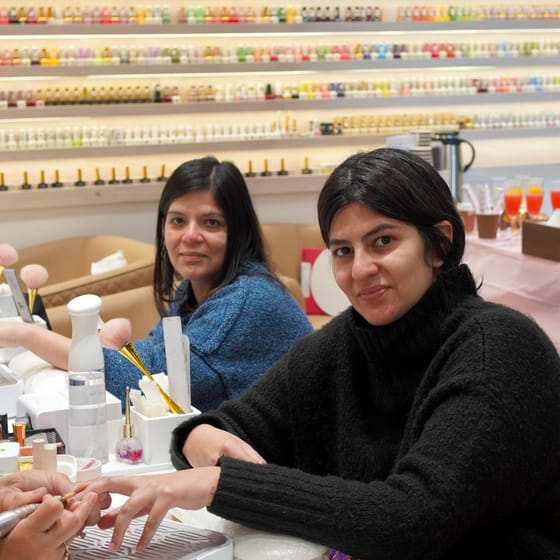 Clients having their nails done in front of the polish wall
