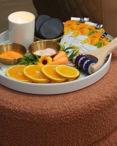 The orange pedicure ritual tray with a candle, scrubs and fresh orange slices